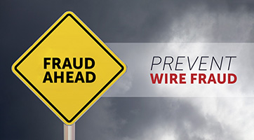 Yellow Fraud Ahead caution sign against gray cloudy background with Prevent Wire Fraud to the side