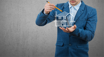 Man in blue suit holding a sketched house pointing his pencil at the roof