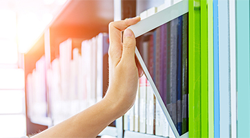 a hand grabbing a tablet out of a book shelve 