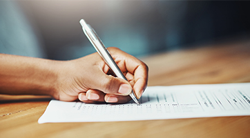 a picture of a hand signing a piece of paper