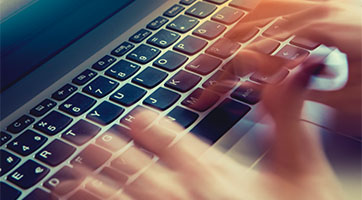 hands typing on a laptop keyboard