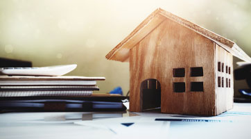 an image of a model house next to a pile of documents