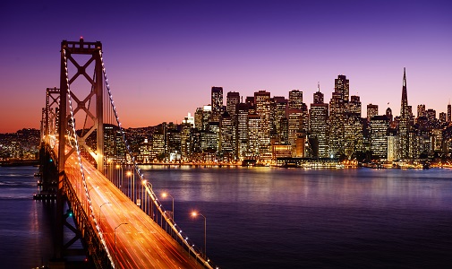 an image of a lit up bridge over a body of water leading towards a city