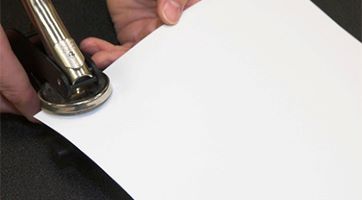 Hand using notary stamp on a piece of paper
